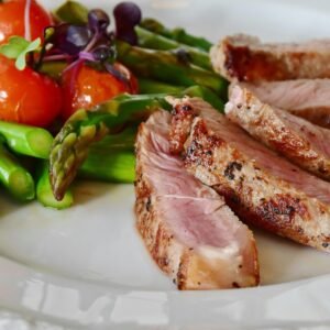 Close-up of grilled steak slices with asparagus and cherry tomatoes, perfect for a healthy meal.