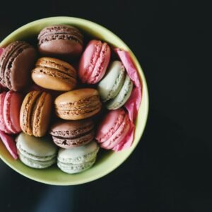 A vibrant assortment of macarons in a green bowl, perfect for dessert themes.